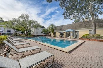 a swimming pool with chairs and a house in the background